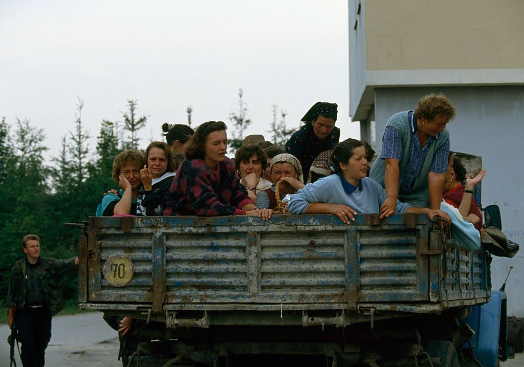 Woman being loaded up into army trucks to be processed.