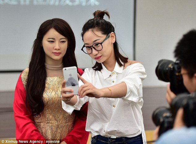 Girls takes a selfie with a Chinese robot.