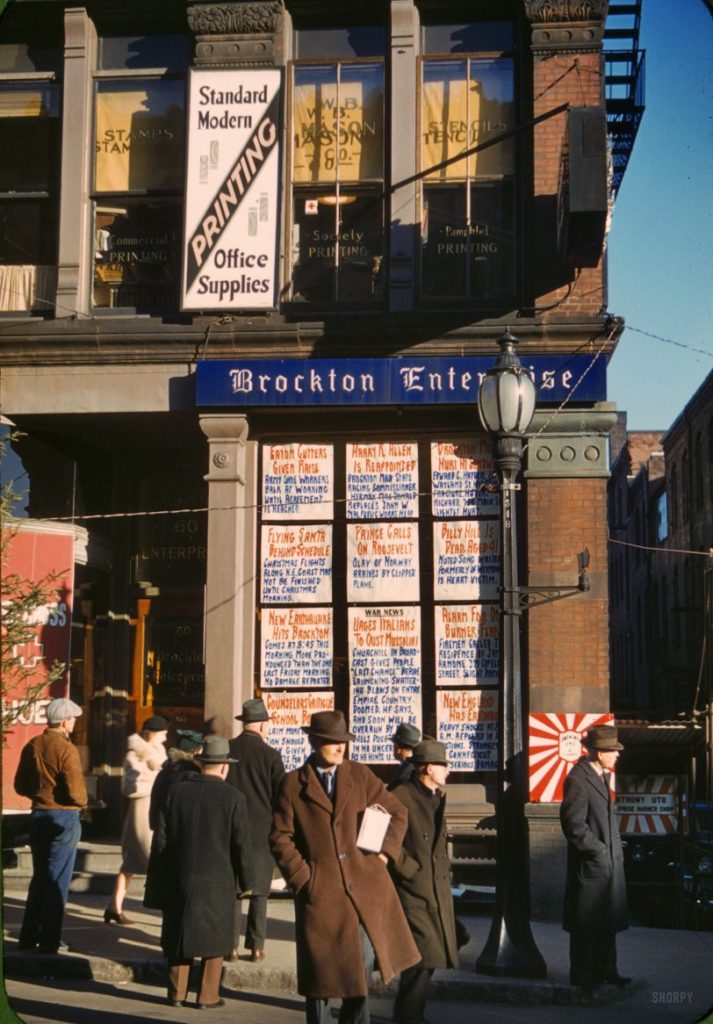 December 1940. Brockton, Massachusetts. "Men and a woman reading headlines posted in window of Brockton Enterprise newspaper office on Christmas Eve." 35mm Kodachrome transparency by Jack Delano.