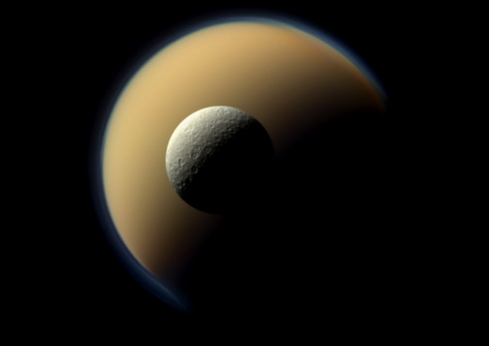 The Saturn moon Rhea in the foreground, with Titan in the background.